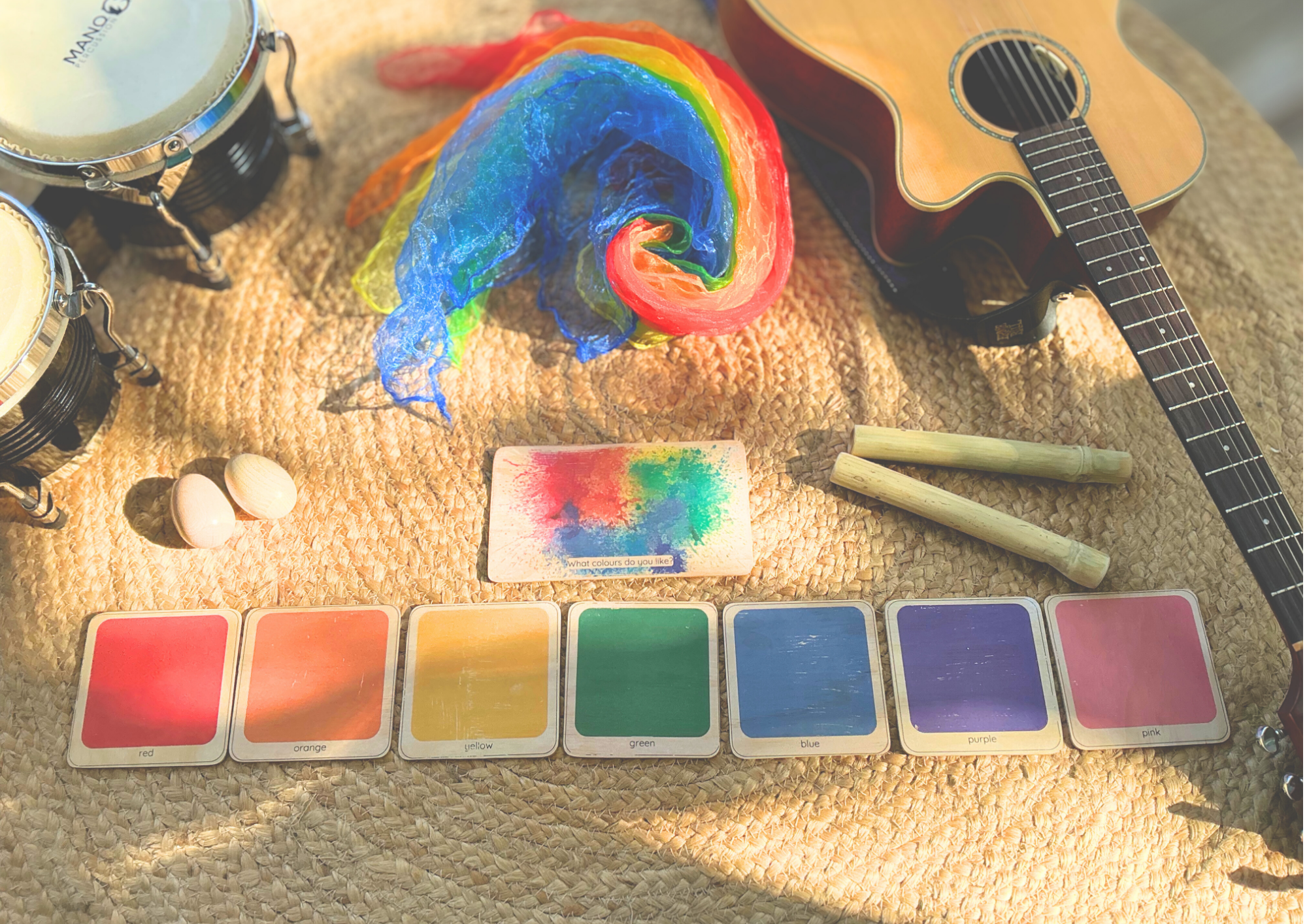 Colour song materials laid out with rainbow scarf, colour cards, guitar and percussion instruments